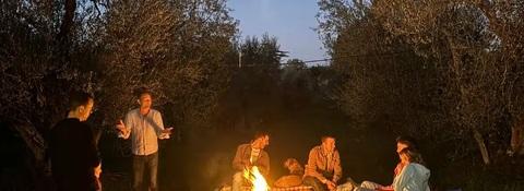 Small group gathered around a fire among the olive trees